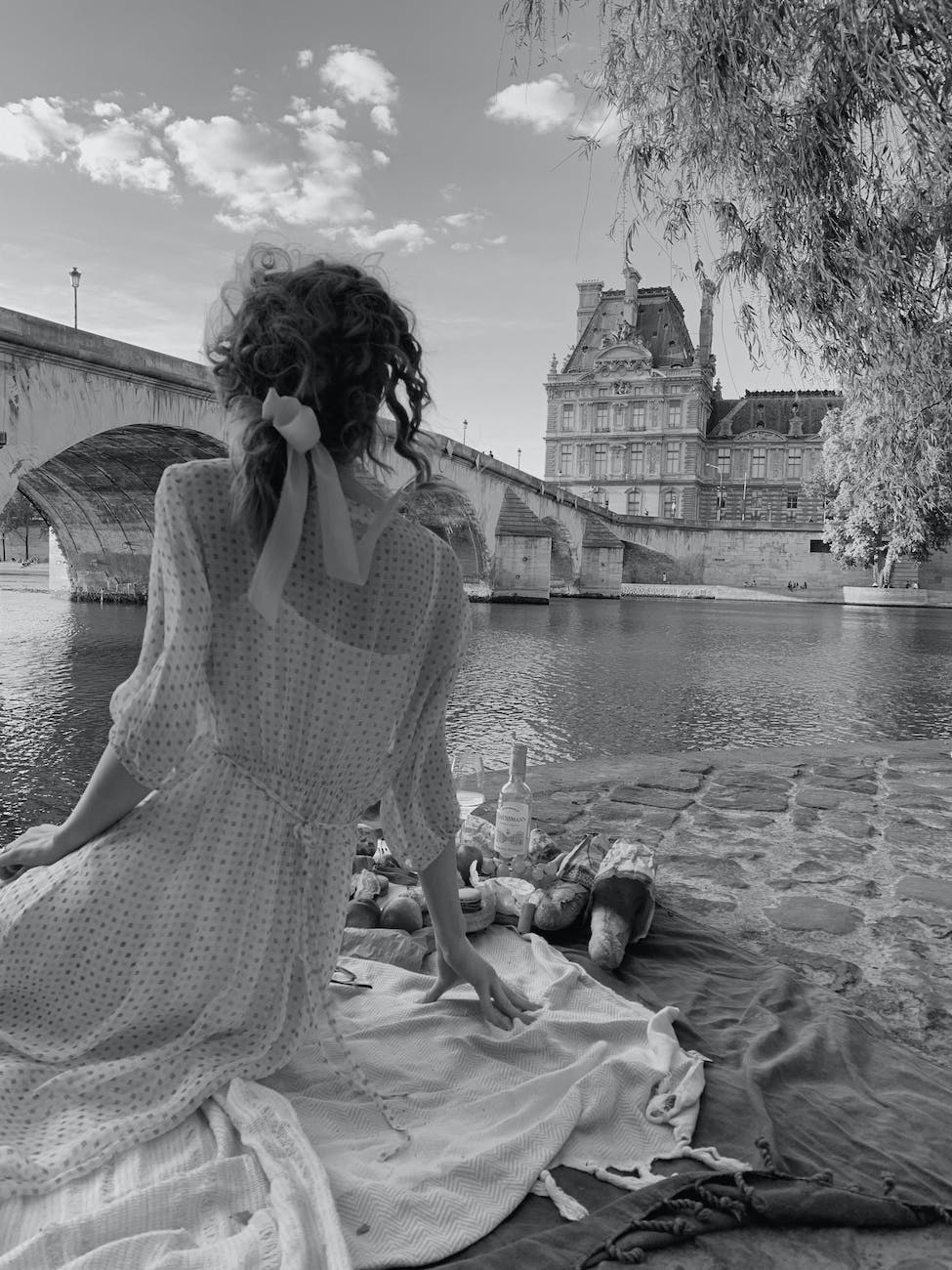 woman sitting on picnic blanket by river shore